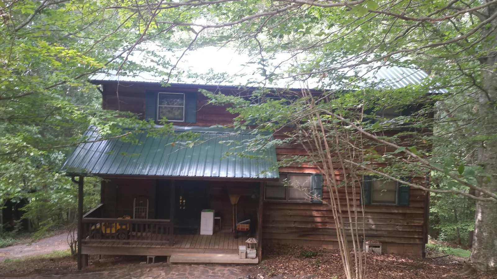 Green metal roof and covered porch on a log cabin in Moxahala