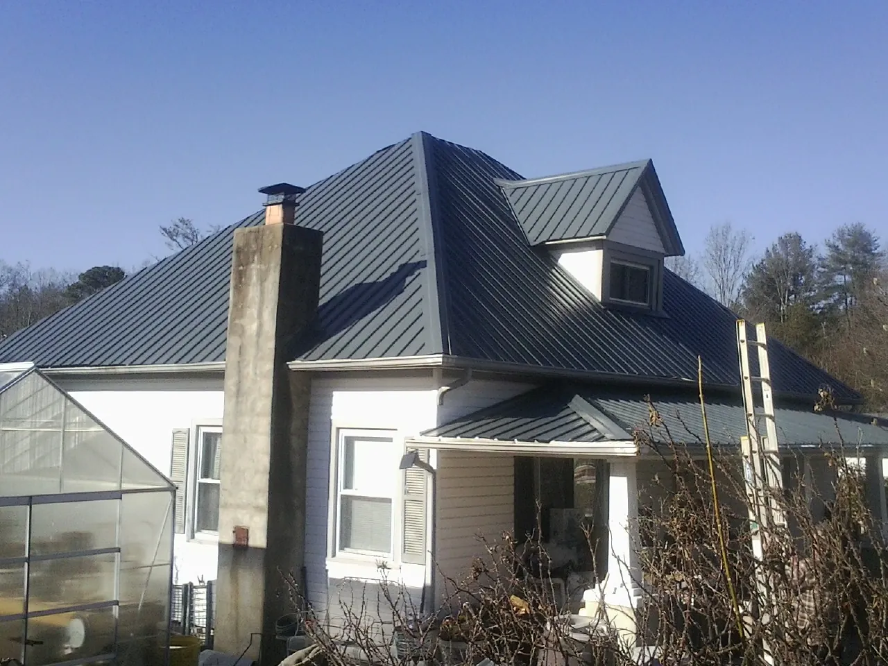Dark blue standing seam metal roof on a white farmhouse with dormer — Slate & Tile Roof Repair by Roofing Brothers in Moxahala
