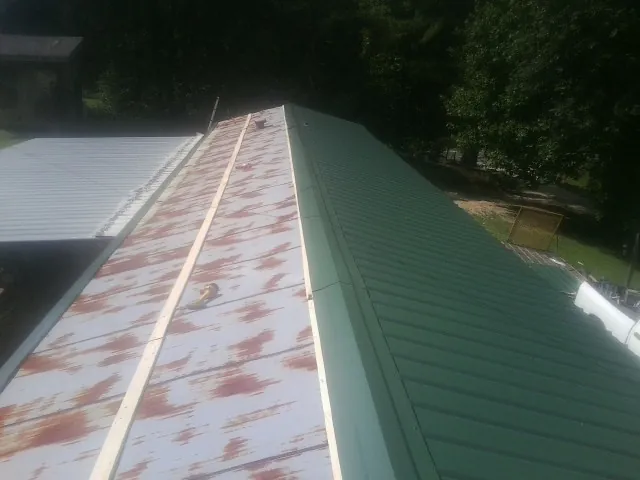 Old rusted panels beside newly installed green metal roofing — Wind Damage Roof Repair by Roofing Brothers in Moxahala