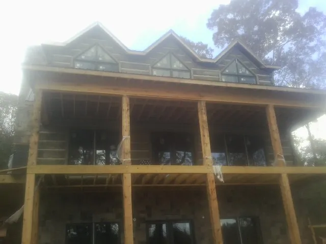 Dormers and porch framing on a large log home under construction — Roof Coating work by our crew in Moxahala