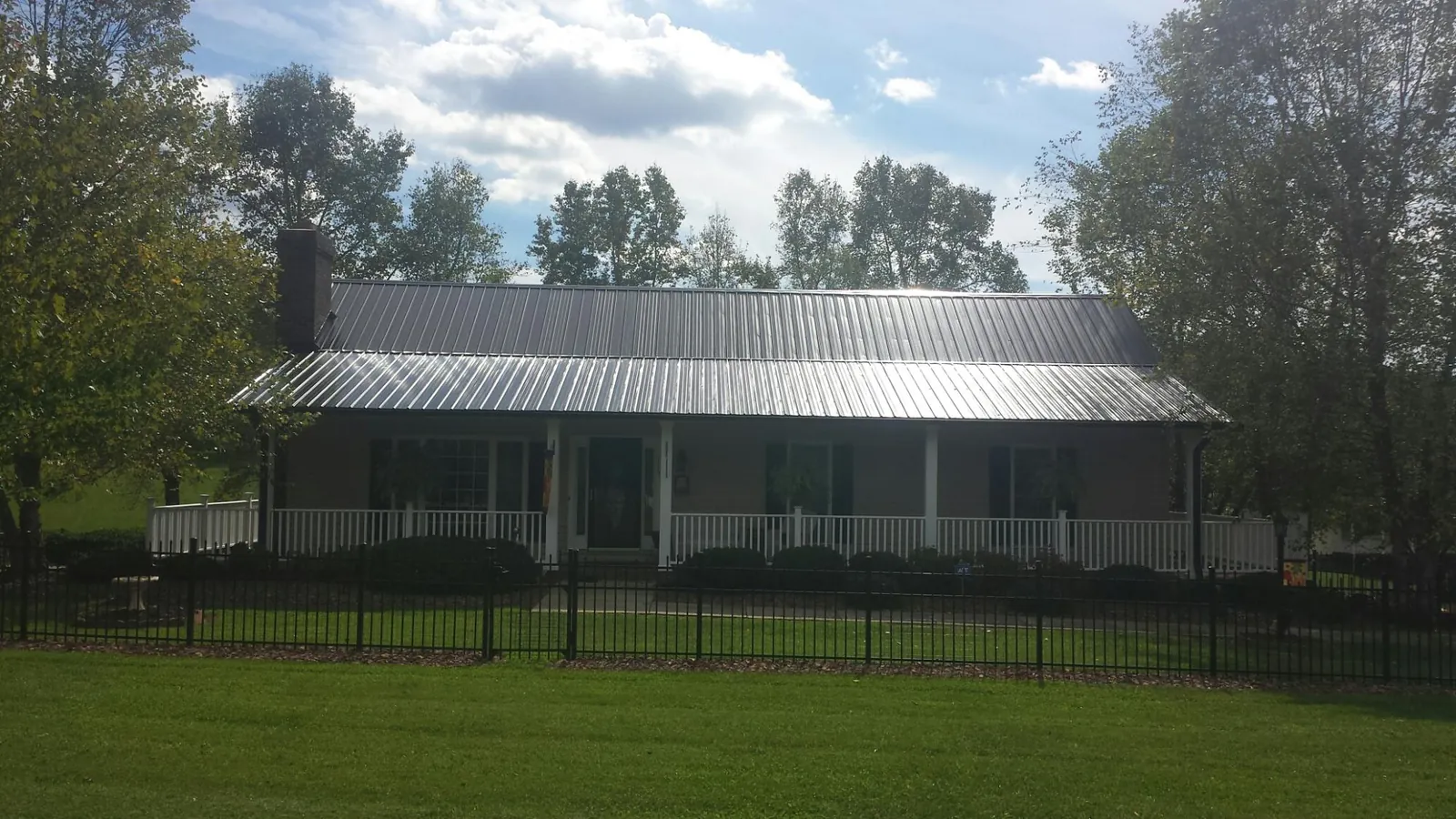 Gray metal roof on a brick ranch with a full width front porch — Gutter Guard Installation work by our crew in Moxahala