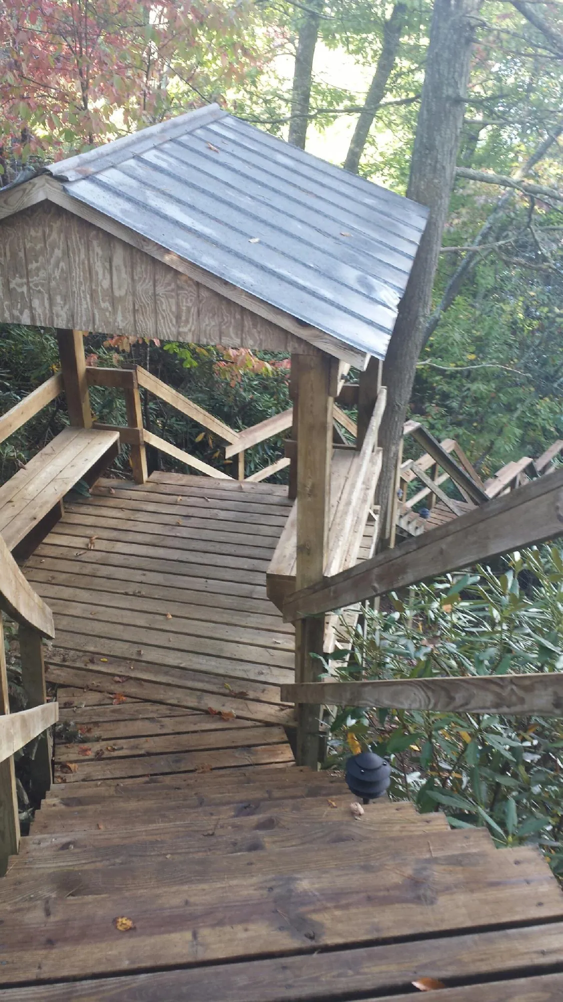 Metal roofed shelter over wooden steps on a wooded walkway — Skylight Repair & Installation work by our crew in Moxahala