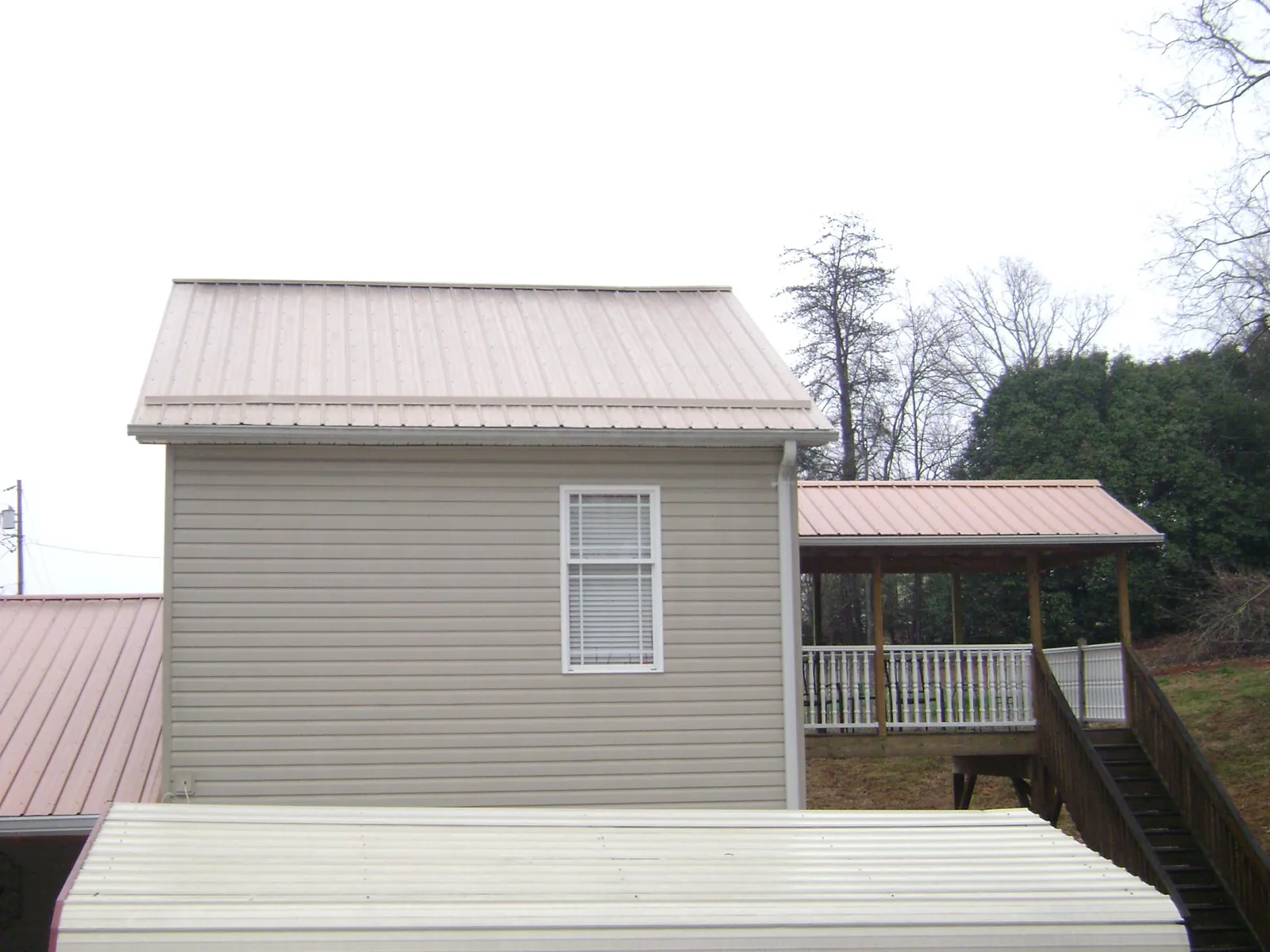 Tan metal roofs on a two story addition and attached porch, from a Roof Replacement job in Moxahala