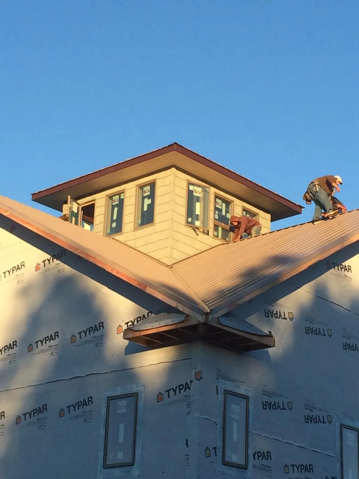 Roofers working around a rooftop cupola on a new metal roof at sunset — Roof Waterproofing in Moxahala by Roofing Brothers